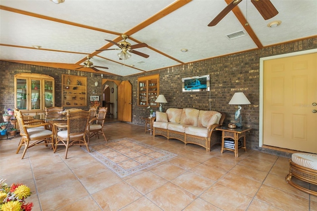 living room featuring brick wall, light tile flooring, and ceiling fan