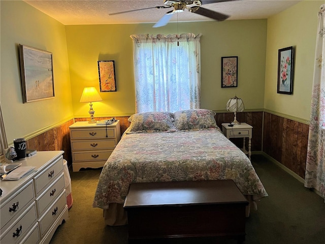 bedroom featuring a textured ceiling, dark carpet, and ceiling fan