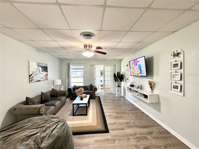 living room with a paneled ceiling, wood-type flooring, ceiling fan, and french doors