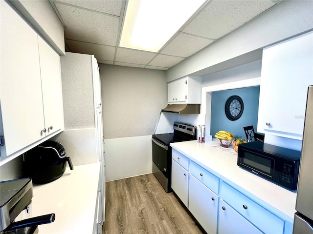 kitchen with a paneled ceiling, stainless steel appliances, white cabinetry, and light hardwood / wood-style flooring