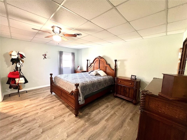 bedroom featuring ceiling fan, a drop ceiling, and light wood-type flooring