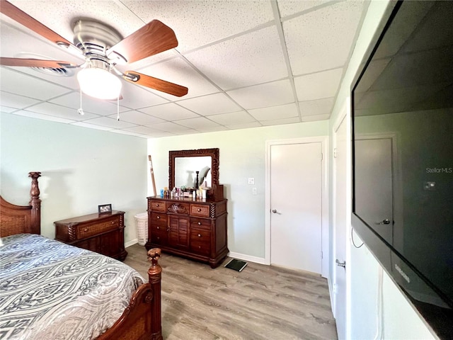 bedroom with light hardwood / wood-style floors, ceiling fan, and a paneled ceiling