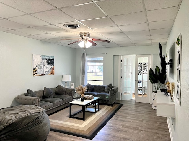 living room featuring hardwood / wood-style floors, ceiling fan, a drop ceiling, and french doors