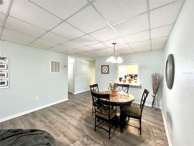 dining area featuring dark hardwood / wood-style flooring, a chandelier, and a paneled ceiling