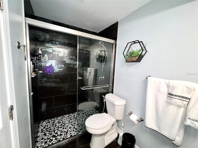 bathroom with a shower with door and toilet