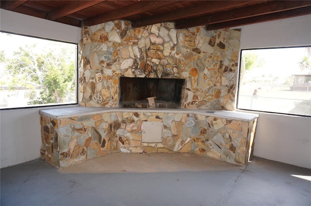 interior space featuring beam ceiling, a fireplace, wooden ceiling, and concrete flooring