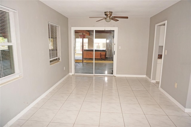 tiled empty room with ceiling fan and a wealth of natural light