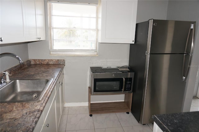 kitchen with white cabinetry, appliances with stainless steel finishes, light tile floors, and sink