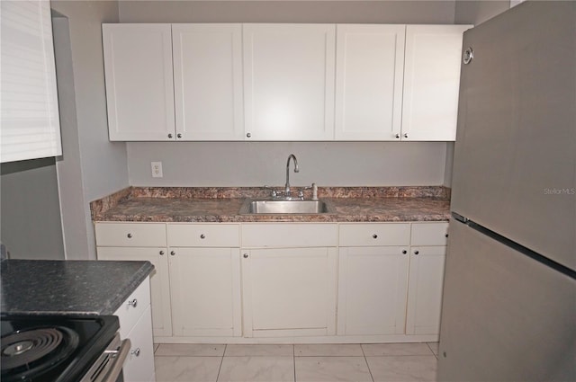 kitchen with stainless steel electric range, sink, white fridge, white cabinets, and light tile flooring