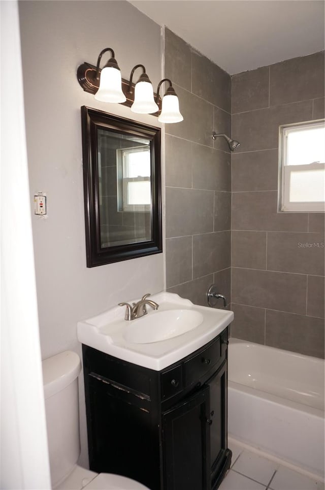 full bathroom with tile floors, toilet, vanity, and tiled shower / bath