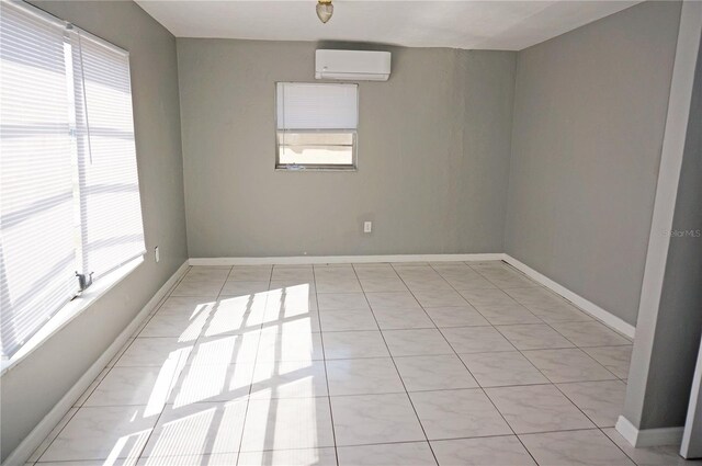 unfurnished room with plenty of natural light, light tile floors, and a wall unit AC