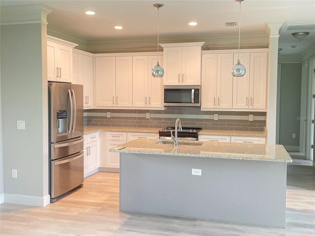 kitchen with appliances with stainless steel finishes, light hardwood / wood-style flooring, decorative light fixtures, and backsplash