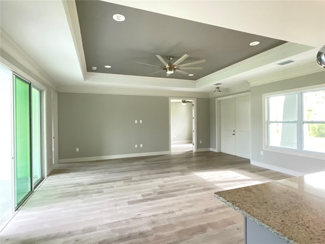 2563 Longworthy Rd, North Port, FL 34288 - unfurnished living room with visible vents, a tray ceiling, ceiling fan, light wood-style floors, and crown molding