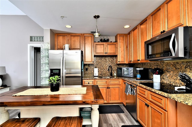 kitchen featuring pendant lighting, dark stone counters, appliances with stainless steel finishes, backsplash, and a breakfast bar area