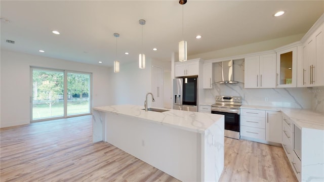 kitchen featuring white cabinetry, hanging light fixtures, wall chimney exhaust hood, and stainless steel appliances