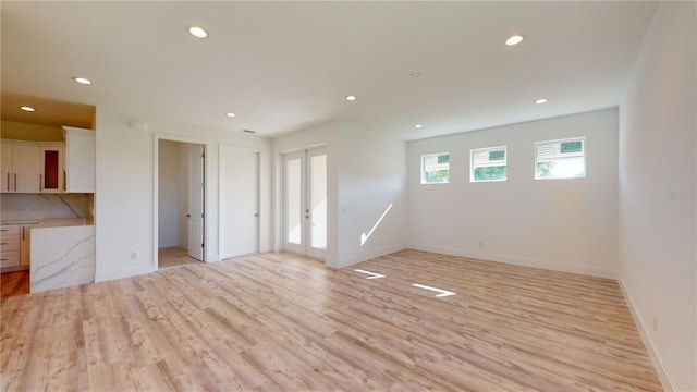 unfurnished living room featuring french doors and light hardwood / wood-style flooring