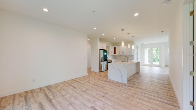 kitchen featuring decorative backsplash, light wood-type flooring, sink, decorative light fixtures, and white cabinetry