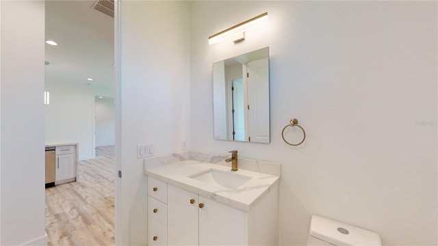 bathroom with hardwood / wood-style flooring, vanity, and toilet