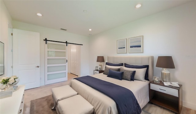 bedroom featuring a barn door and light hardwood / wood-style floors