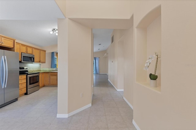 kitchen featuring light tile flooring, backsplash, light brown cabinets, and appliances with stainless steel finishes