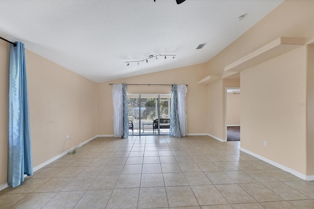 tiled empty room with lofted ceiling, a textured ceiling, and rail lighting