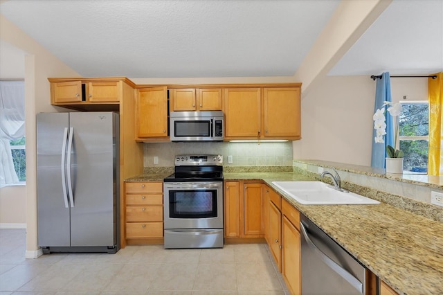 kitchen featuring light stone countertops, sink, stainless steel appliances, light tile floors, and tasteful backsplash