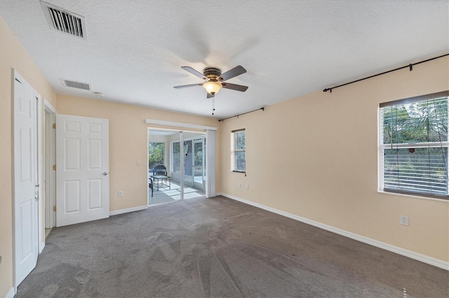 carpeted empty room with a textured ceiling, ceiling fan, and a healthy amount of sunlight