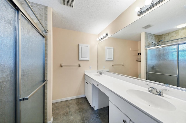 bathroom with double sink, walk in shower, a textured ceiling, tile flooring, and large vanity