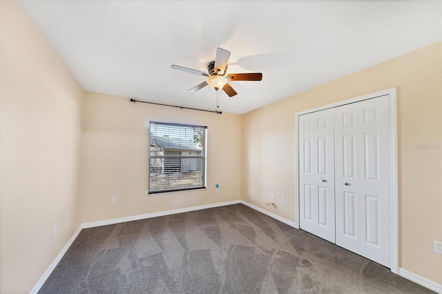 unfurnished bedroom featuring a closet, dark colored carpet, and ceiling fan