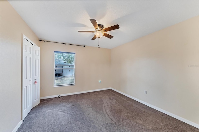 interior space with dark carpet and ceiling fan