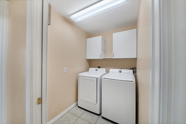 clothes washing area with cabinets, a textured ceiling, independent washer and dryer, and light tile flooring