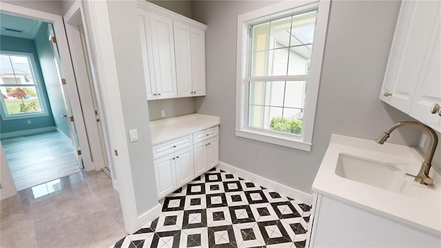 clothes washing area with light tile patterned flooring and sink