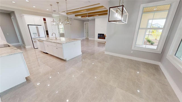 kitchen featuring decorative light fixtures, a kitchen island with sink, light stone counters, and white cabinetry