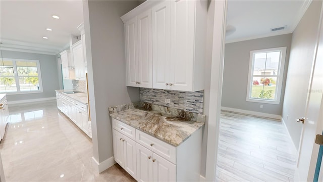 kitchen featuring a healthy amount of sunlight, backsplash, and white cabinetry