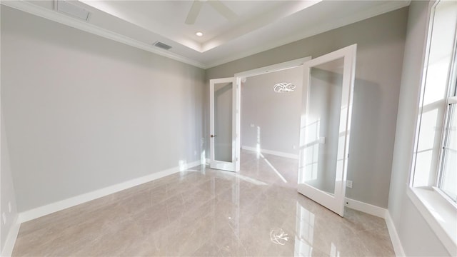 empty room featuring ceiling fan, french doors, a tray ceiling, and ornamental molding