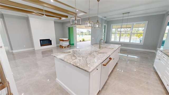 kitchen featuring pendant lighting, white cabinets, beamed ceiling, sink, and a center island with sink