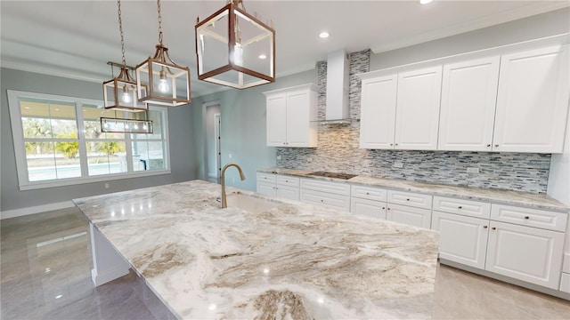 kitchen with white cabinetry, a center island with sink, hanging light fixtures, wall chimney range hood, and sink