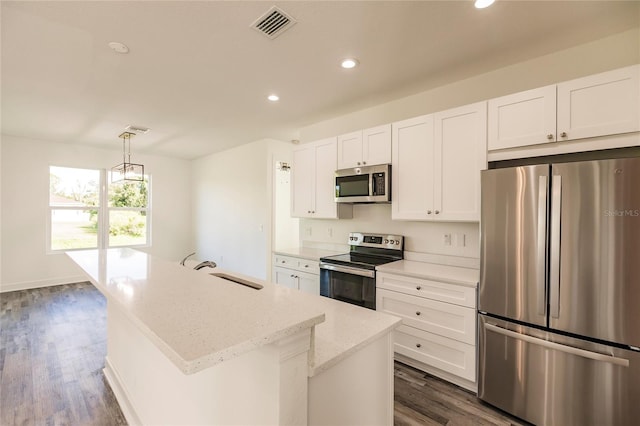 kitchen featuring hanging light fixtures, dark hardwood / wood-style flooring, a center island with sink, stainless steel appliances, and white cabinetry