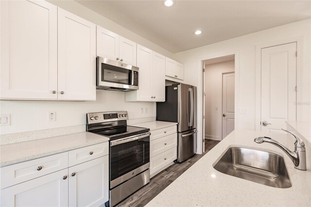 kitchen with appliances with stainless steel finishes, dark hardwood / wood-style flooring, sink, and white cabinetry