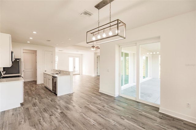 kitchen featuring decorative light fixtures, wood-type flooring, white cabinetry, and dishwasher