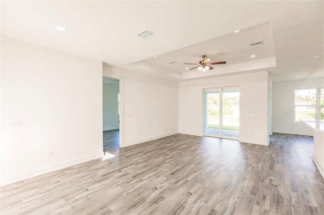 empty room featuring light hardwood / wood-style flooring, a raised ceiling, and ceiling fan