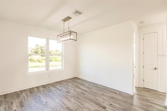 spare room with an inviting chandelier and light hardwood / wood-style flooring