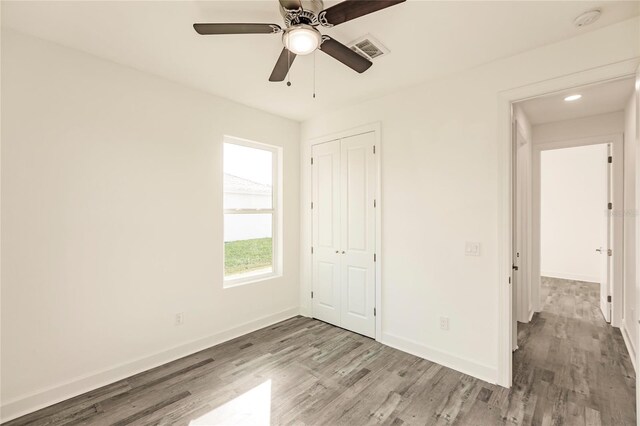 unfurnished bedroom with ceiling fan, a closet, and dark wood-type flooring