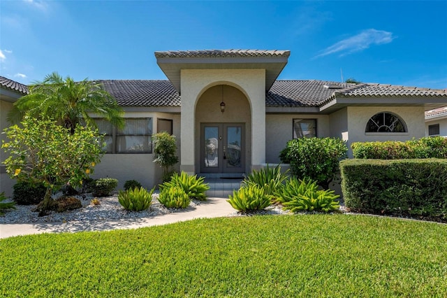 mediterranean / spanish house featuring french doors and a front lawn