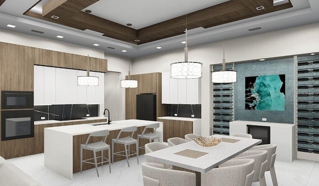 kitchen featuring a kitchen island with sink, light tile floors, a breakfast bar area, decorative light fixtures, and a notable chandelier