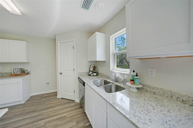 kitchen with sink, light stone counters, white cabinets, dishwasher, and light hardwood / wood-style flooring