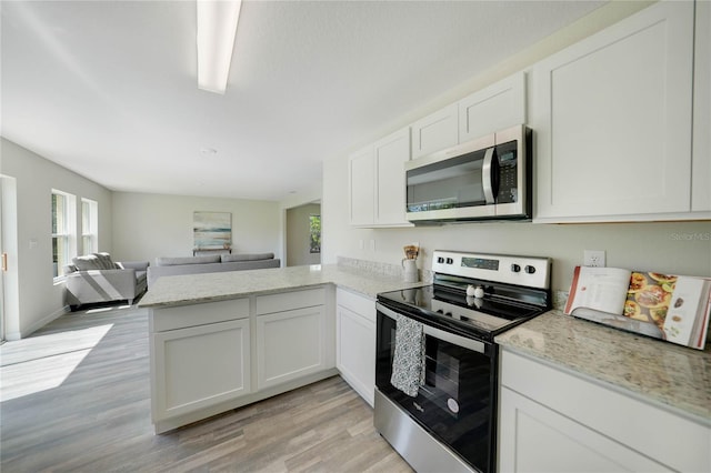 kitchen featuring kitchen peninsula, white cabinetry, appliances with stainless steel finishes, light hardwood / wood-style floors, and light stone counters