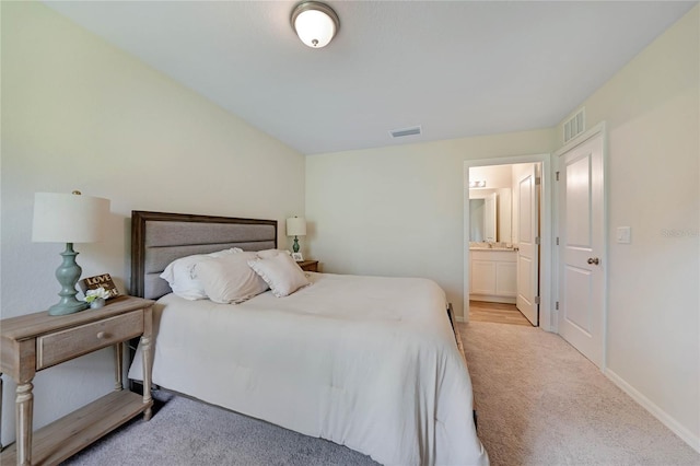 bedroom with light colored carpet and ensuite bath