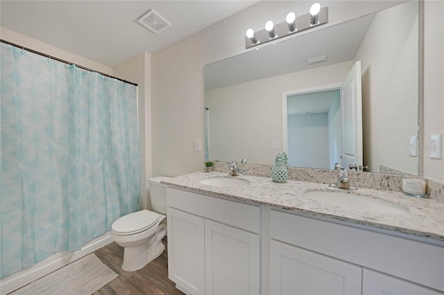 bathroom with hardwood / wood-style floors, toilet, dual sinks, and large vanity