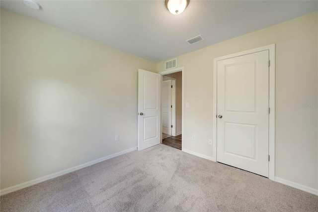 unfurnished bedroom featuring light carpet and a closet